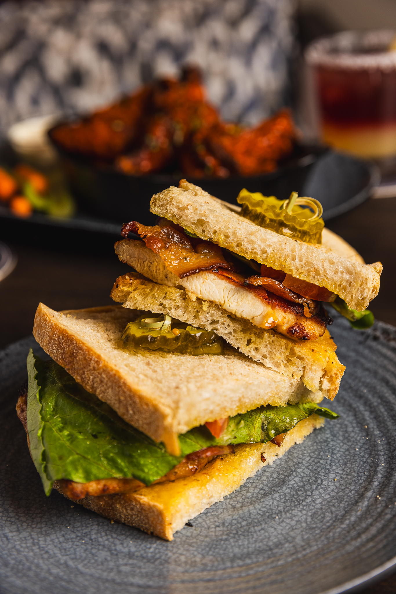 Stacked sandwich with grilled chicken, bacon, lettuce, tomato and pickles on toasted sourdough from The Placery
