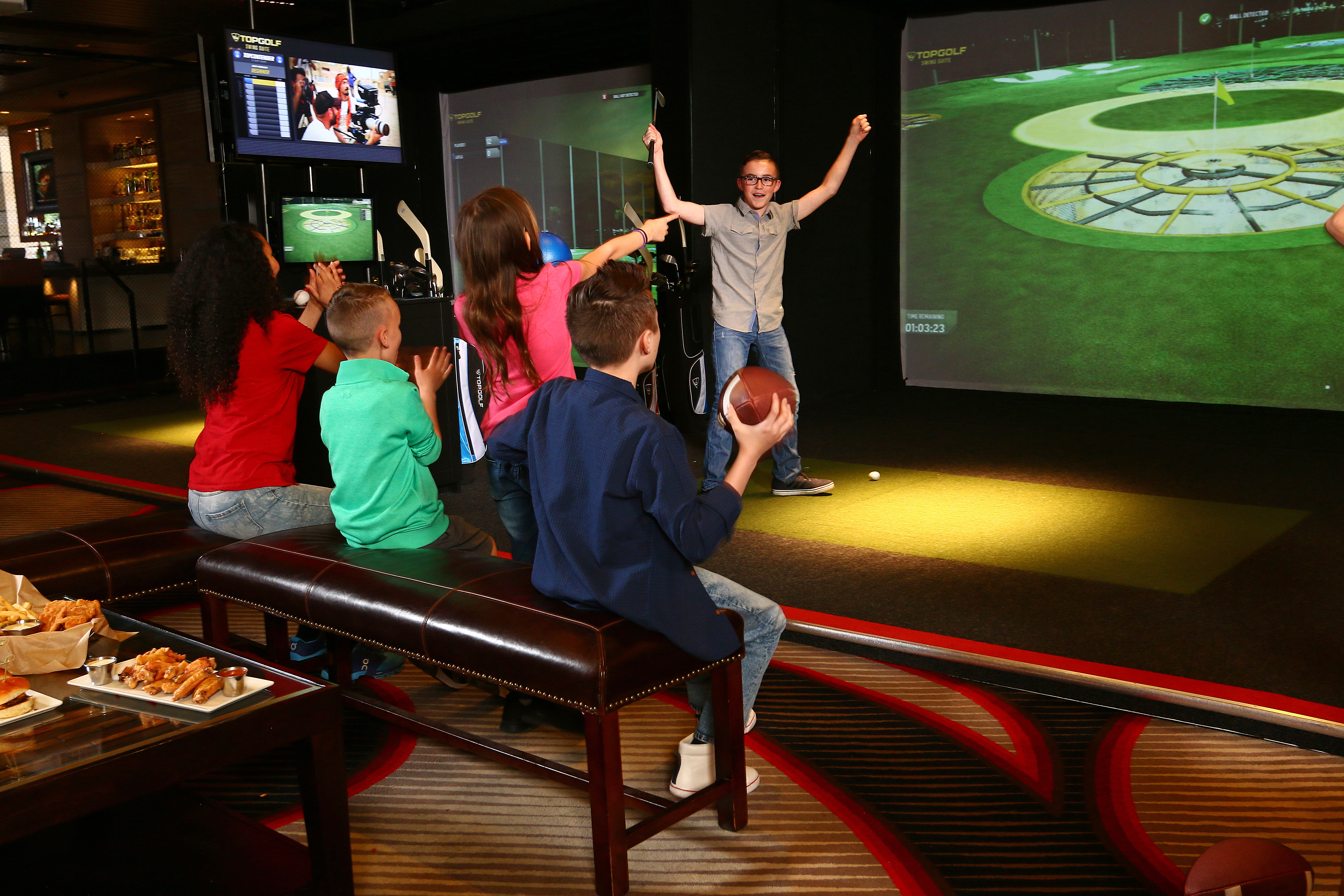Group of kids celebrating a successful round with arms raised in the Swing Suite bay
